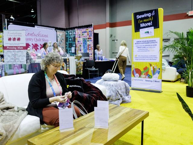 An attendee knitting on a sofa in the Creative Hub lounge
