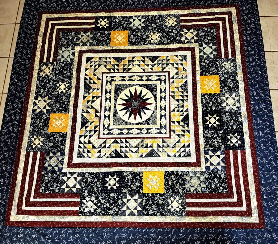 A concentric medallion quilt in black, cream and deep red with a compass rose at its centre